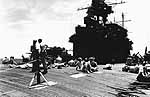 Men relax on Enterprise CV-6's buckled flight deck, as she returns to Pearl Harbor, May 1945.