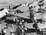 Flight deck crews begin to disentangle planes damaged by an Avenger that missed the arresting wires.