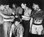 M. J. Carlson AMM 1/c grimaces while squadron-mates cut his hair: pollywog initiation, 22 Jan 1944.