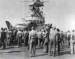 Plane handlers gather around a Bombing Twenty SB2C Helldiver that has crashed on the flight deck.