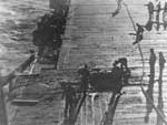 Crewmen aboard Enterprise CV-6 examine bomb damage, 24 August 1942.