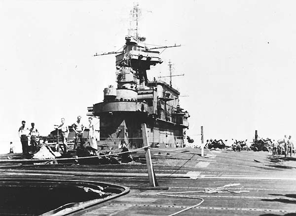 Crewmen inspect the 20-ft hole left in Enterprise's flight deck by the 14 May 1945 Kamikaze attack.