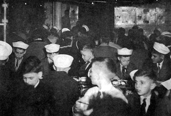 Young men from a nearby orphanage enjoy a special Christmas dinner aboard the Big E, 1945.